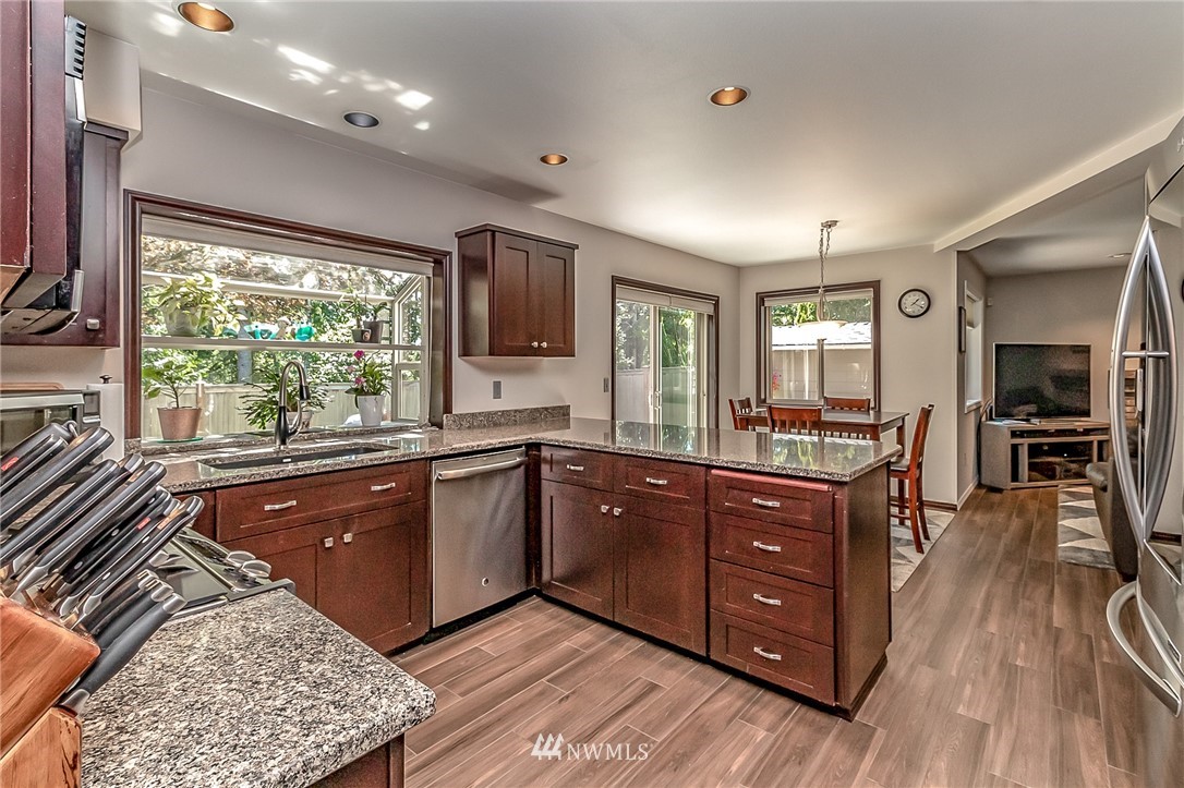 3126 210th Street Southeast Bothell, WA 98021 - Photo 6 of 33 a kitchen with stainless steel appliances granite countertop sink stove and wooden cabinets
