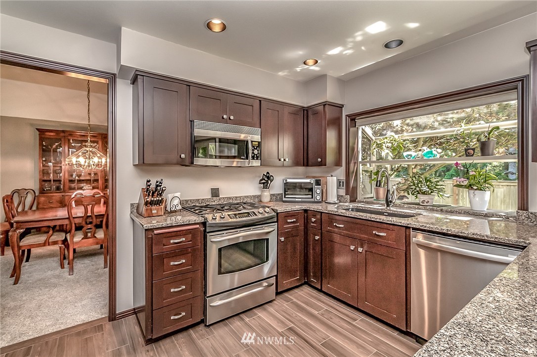 3126 210th Street Southeast Bothell, WA 98021 - Photo 7 of 33 a kitchen with stainless steel appliances granite countertop a stove top oven