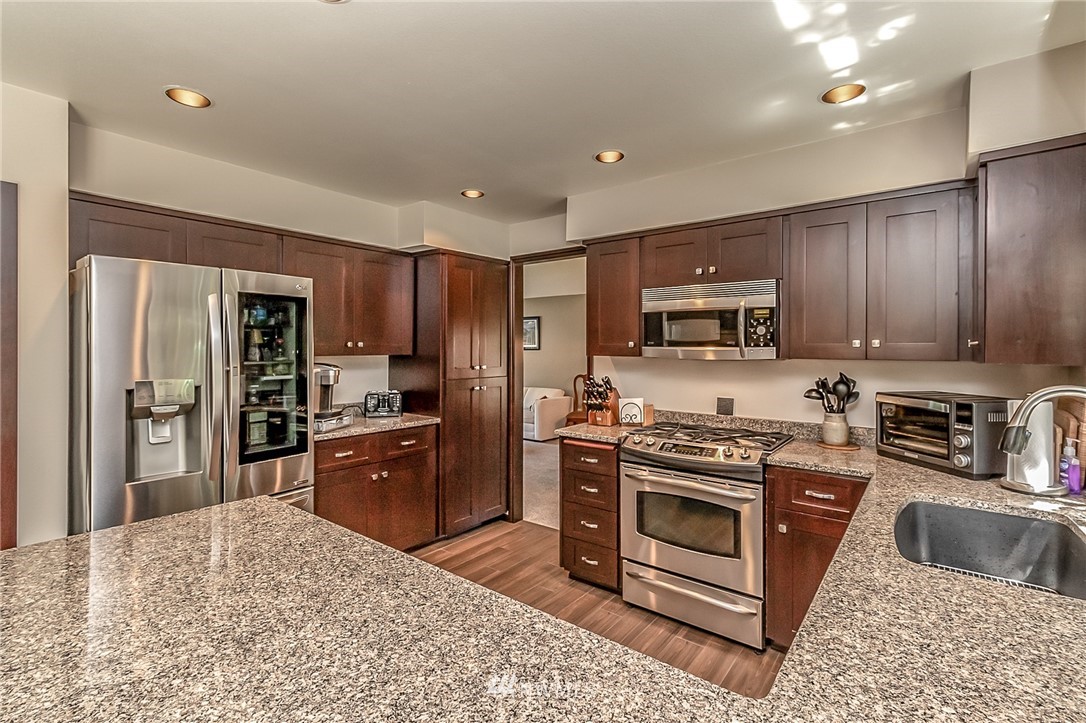 3126 210th Street Southeast Bothell, WA 98021 - Photo 8 of 33 a kitchen with stainless steel appliances granite countertop a stove refrigerator sink and microwave