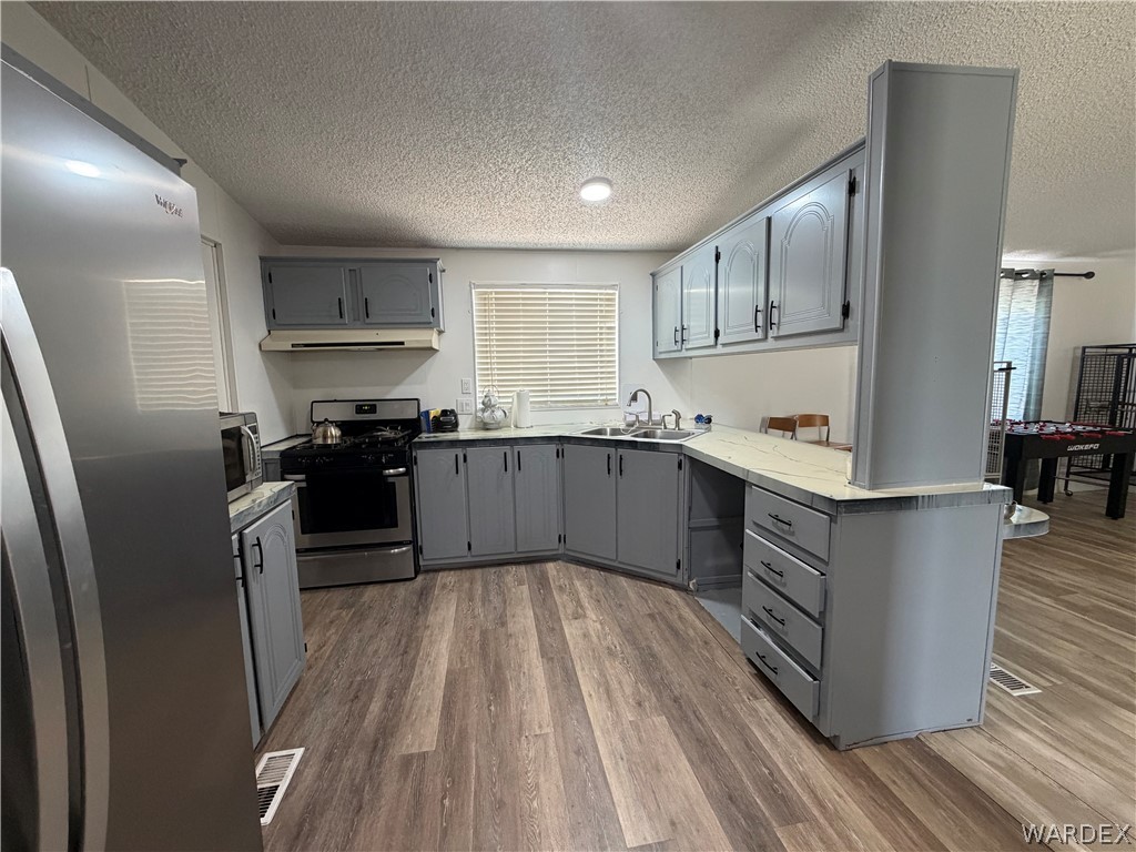 1910 Rio Grande Road Bullhead City, AZ 86442 - Photo 14 of 29 U-shaped kitchen featuring grey cabinetry, wood-finish flooring, and stainless steel appliances