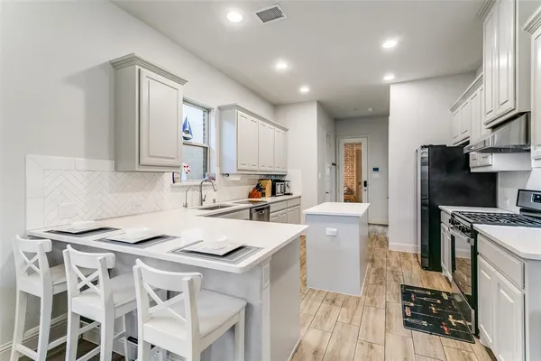 a kitchen with a sink a stove a refrigerator and white cabinets
