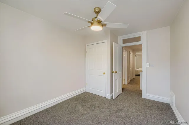 a view of an empty room and a chandelier fan