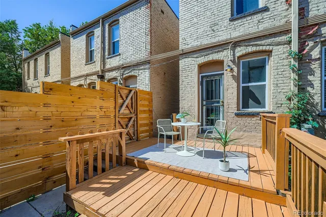 a view of a patio with table and chairs with wooden floor and fence