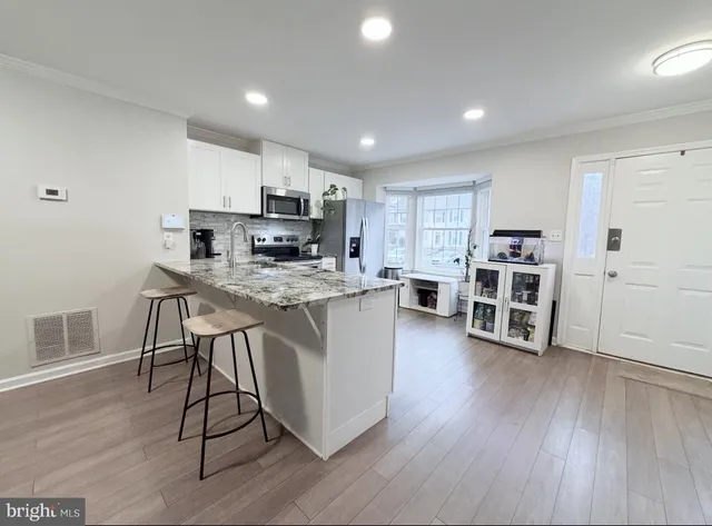 a kitchen with stainless steel appliances a stove top oven a sink dishwasher and a refrigerator with wooden floor