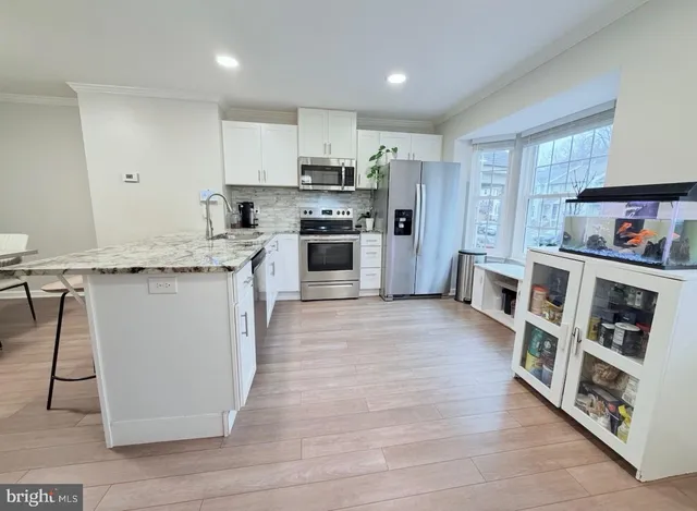 a kitchen with stainless steel appliances granite countertop a stove top oven a sink and a refrigerator
