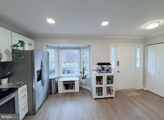 a open kitchen with a refrigerator and wooden floor