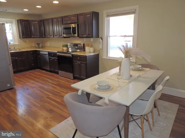 a kitchen with stainless steel appliances granite countertop a sink a stove a dining table and chairs