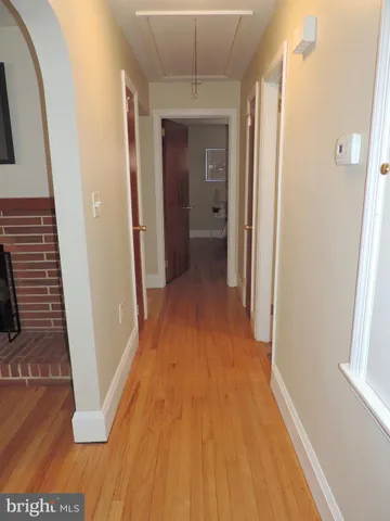 a view of a hallway with wooden floor and a bathroom