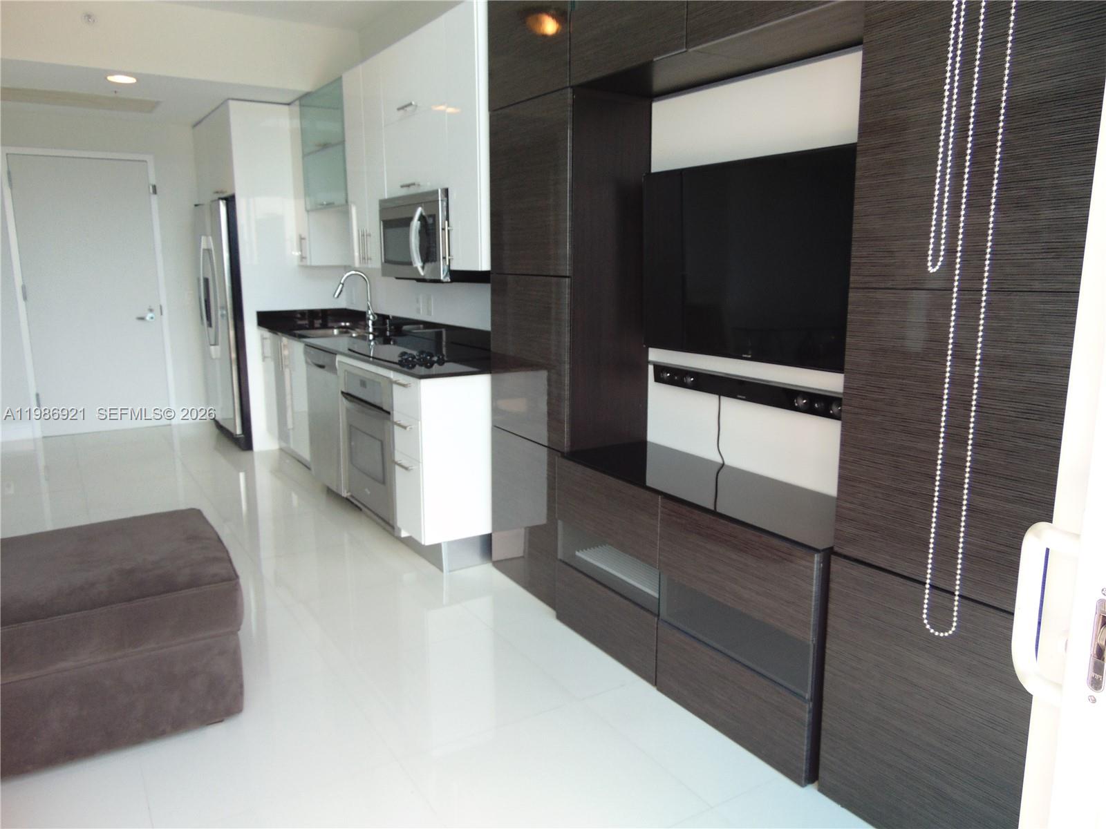 60 Southwest 13th Street, Unit 2619 Miami, FL 33130 - Photo 23 of 27 a kitchen with stainless steel appliances kitchen island granite countertop a stove a microwave and a sink