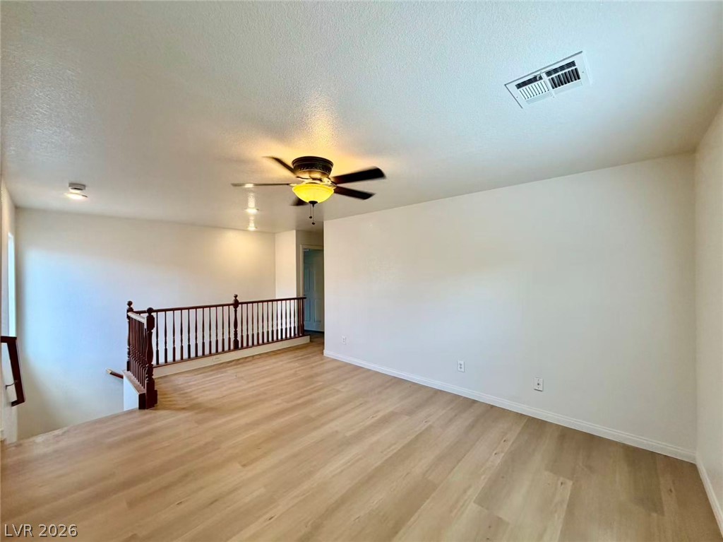 11183 Ranch Valley Street Las Vegas, NV 89179 - Photo 6 of 19 A well-lit upper-level landing with polished hardwood-style flooring and a classic wood railing.