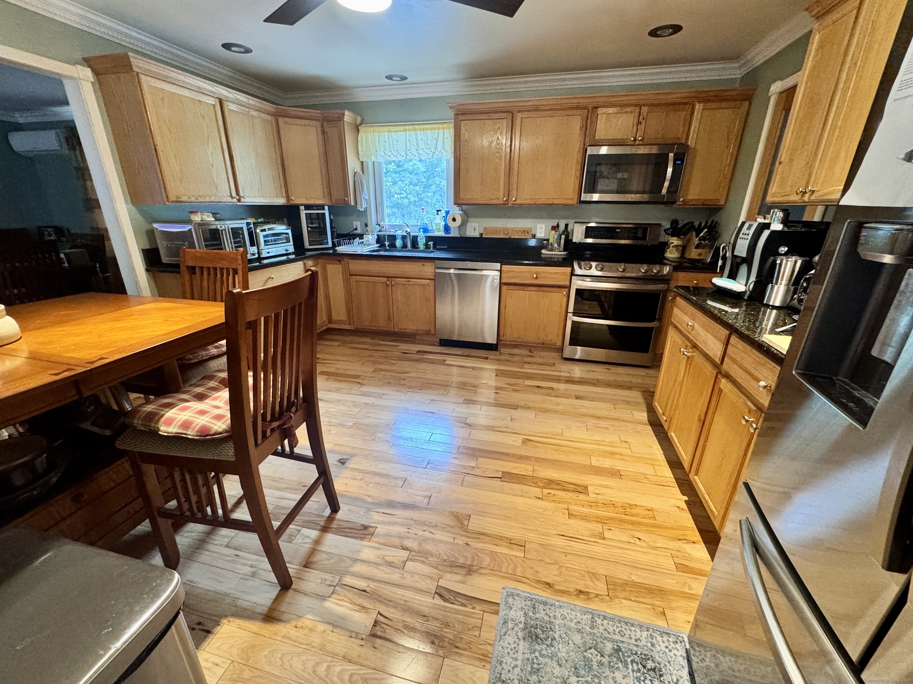 108 Webb Circle Monroe, CT 06468 - Photo 6 of 24 a kitchen with stainless steel appliances kitchen island granite countertop a stove top oven a sink a dining table and chairs with wooden floor