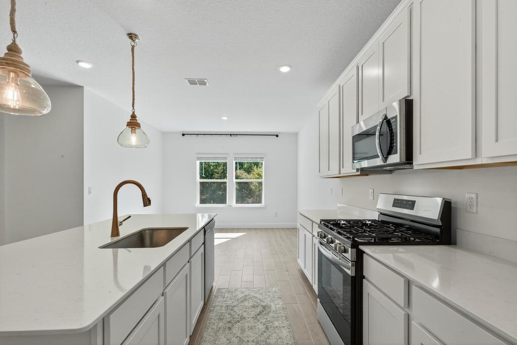 75776 Estuary Way Yulee, FL 32097 - Photo 21 of 83 a kitchen with stainless steel appliances a sink a stove and a wooden floors
