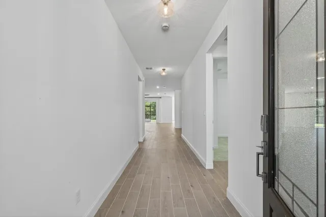 a view of an empty room with a window and wooden floor