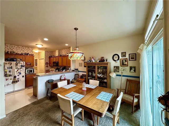 a view of a dining room and livingroom with furniture wooden floor a rug a painting and a chandelier