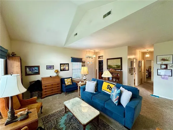 a living room with furniture and a dining table with bookshelf