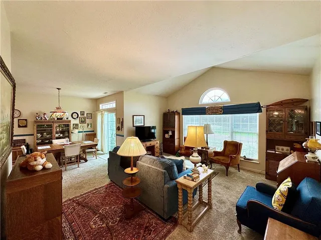 a living room with furniture kitchen view and a large window