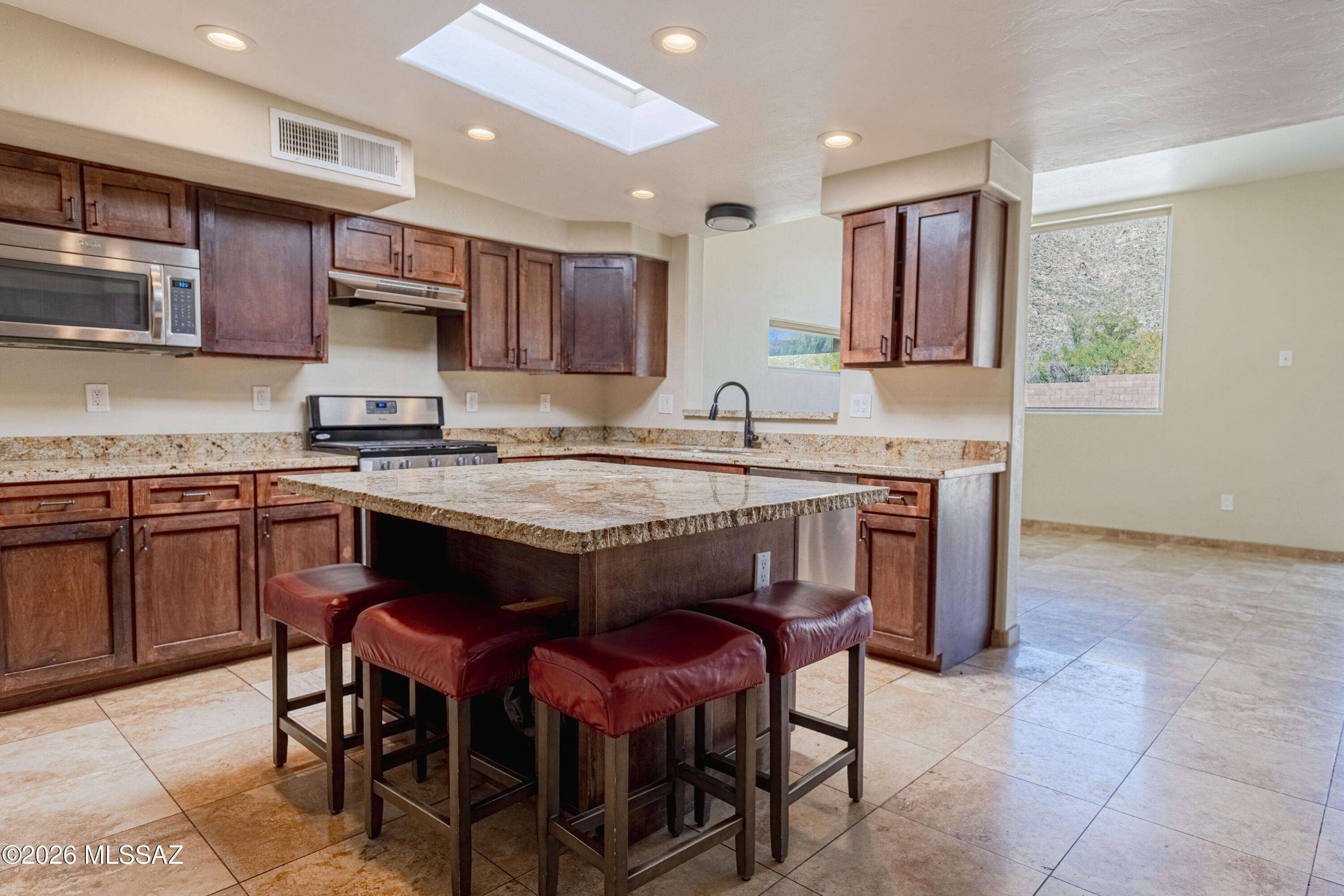 545 East Rancho Catalina Place Tucson, AZ 85704 - Photo 7 of 13 a kitchen with a stove a sink a kitchen island with chairs and wooden cabinets