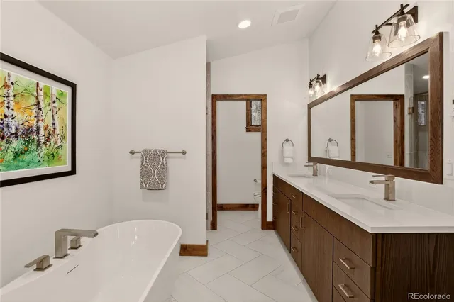 a bathroom with a double vanity sink mirror and bathtub