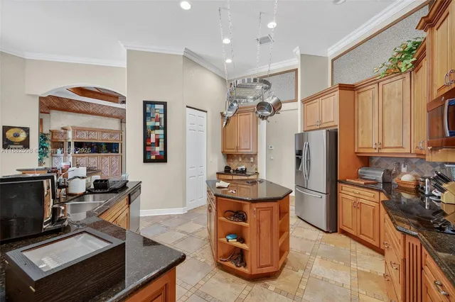 a kitchen with stainless steel appliances kitchen island granite countertop a table chairs in it and a window