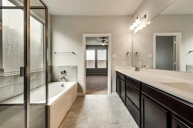 a spacious en suite bathroom with a tub double vanity and a large mirror