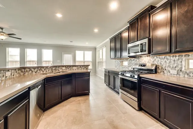 a large kitchen with stainless steel appliances granite countertop a stove sink and cabinets