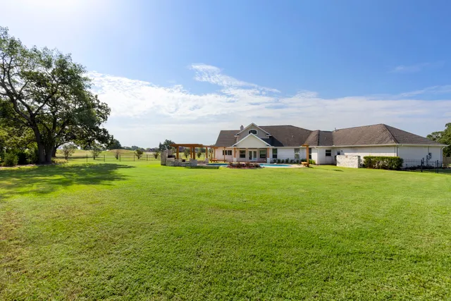 a view of house with garden space and trees in the background