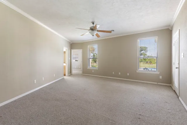 an empty room with windows and ceiling fan