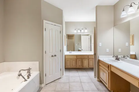 a spacious bathroom with a double vanity sink a mirror and a bathtub