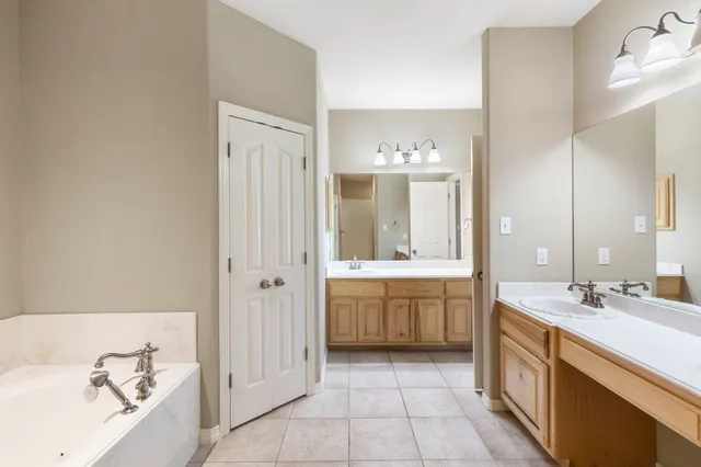 a spacious bathroom with a double vanity sink a mirror and a bathtub