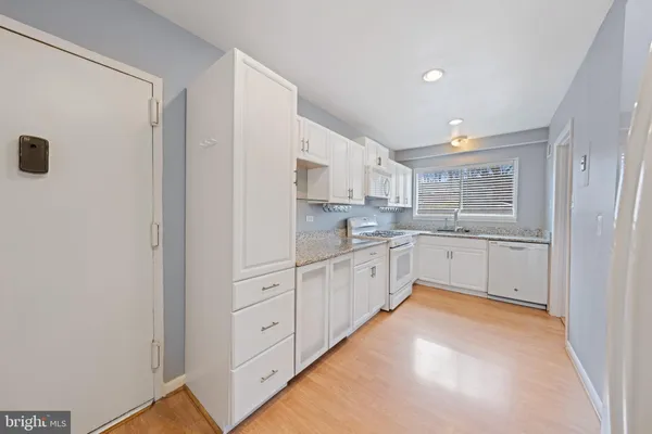 a kitchen with white cabinets and white appliances