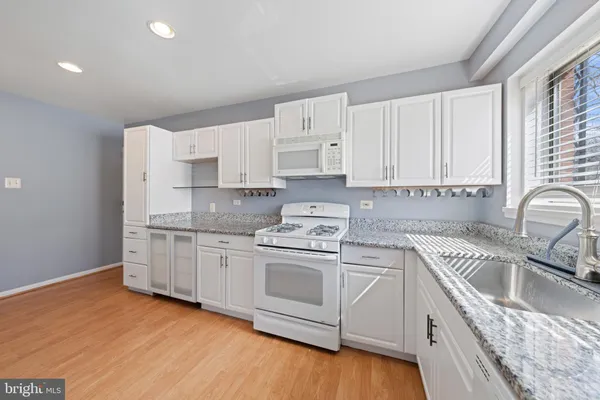 a kitchen with granite countertop white cabinets a sink a window and stainless steel appliances