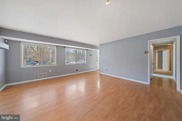 a view of an empty room with window and wooden floor