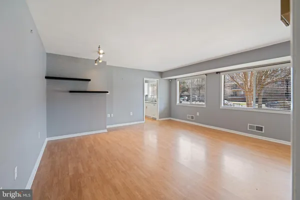 a view of an empty room with a window and wooden floor