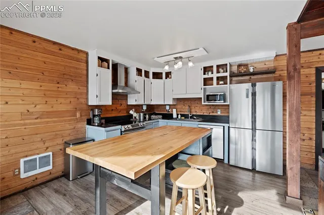 a kitchen with stainless steel appliances a refrigerator a stove a sink cabinets and a dining table