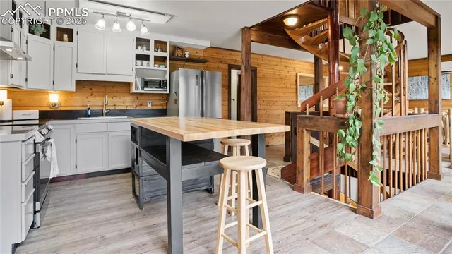 a kitchen with stainless steel appliances kitchen island granite countertop a table chairs and a refrigerator