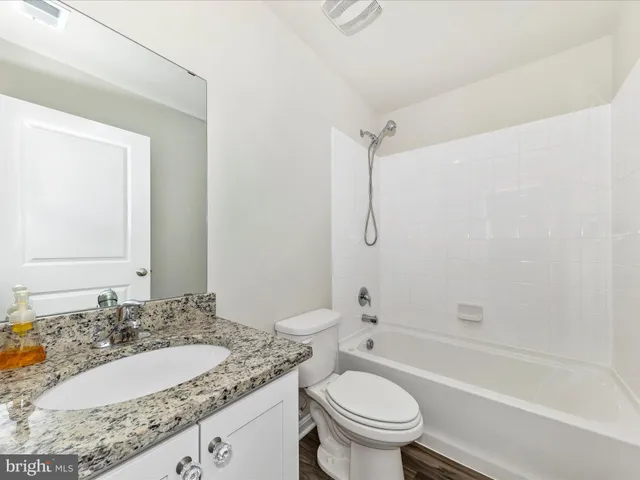a bathroom with a granite countertop sink toilet mirror and shower