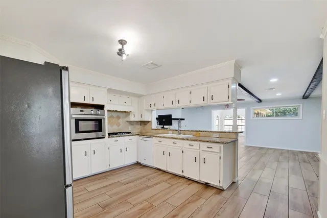 a large kitchen with cabinets wooden floor and stainless steel appliances