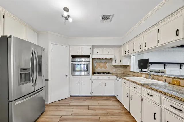 a large kitchen with stainless steel appliances granite countertop a refrigerator sink and cabinets