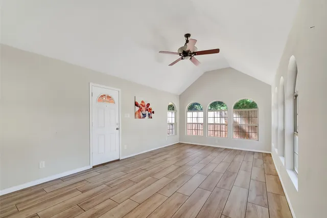 a view of an empty room with a window and wooden floor