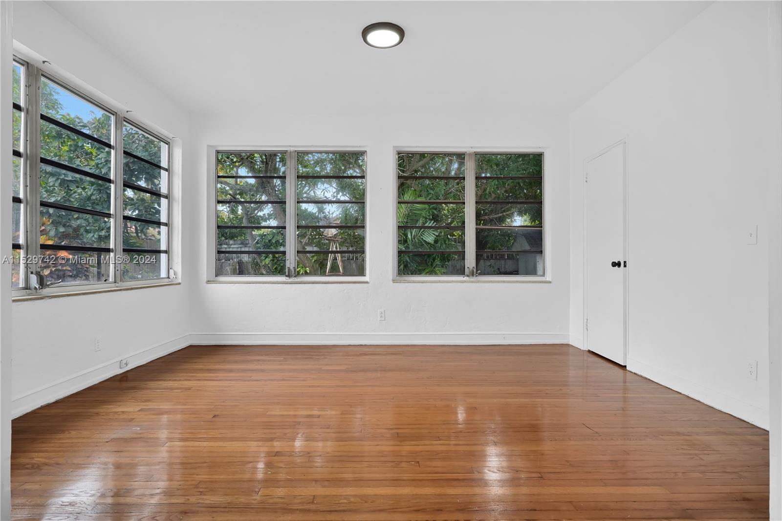 1886 Southwest 16th Terrace Miami, FL 33145 - Photo 7 of 14 a view of an empty room with wooden floor and windows