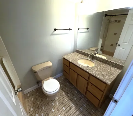 a bathroom with a granite countertop toilet sink and mirror