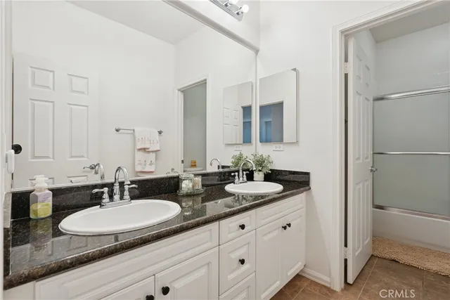a bathroom with a granite countertop sink a large mirror and a bathtub