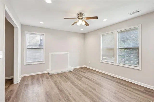 a view of an empty room with wooden floor and a window
