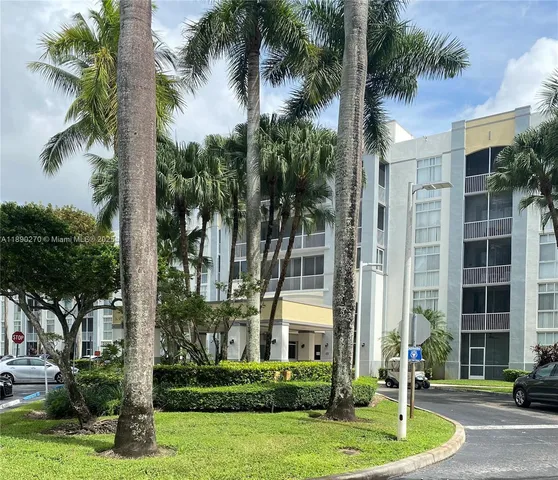 a front view of a building with a garden and trees