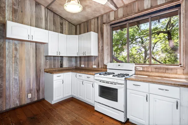 a kitchen with a stove a sink and white cabinets