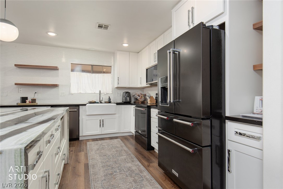 387 Silver Road Mesquite, NV 89027 - Photo 14 of 46 Rich wood floors complement clean white cabinetry and striking stone countertops in this modern kitchen.