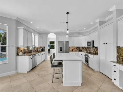 a large white kitchen with a large window and stainless steel appliances