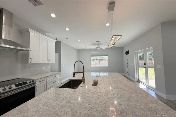 a kitchen with stainless steel appliances kitchen island wooden floors and white walls