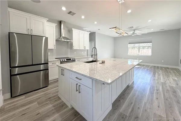 a kitchen with a refrigerator a sink and wooden floor