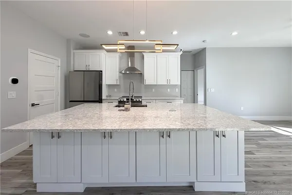 a kitchen with kitchen island granite countertop a sink and refrigerator